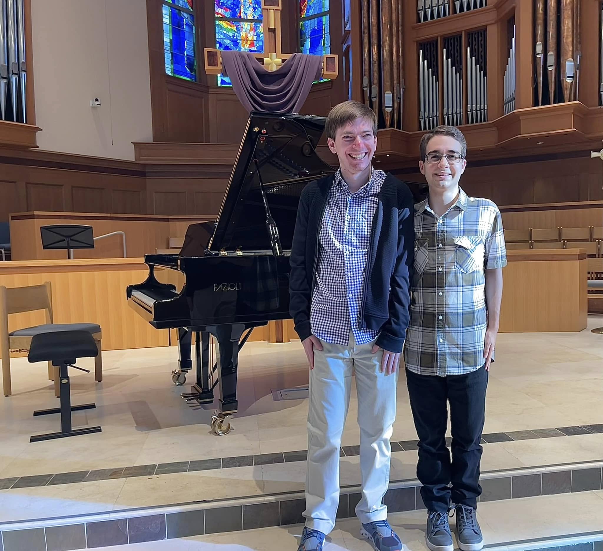 Two students at a grand piano in a concert hall