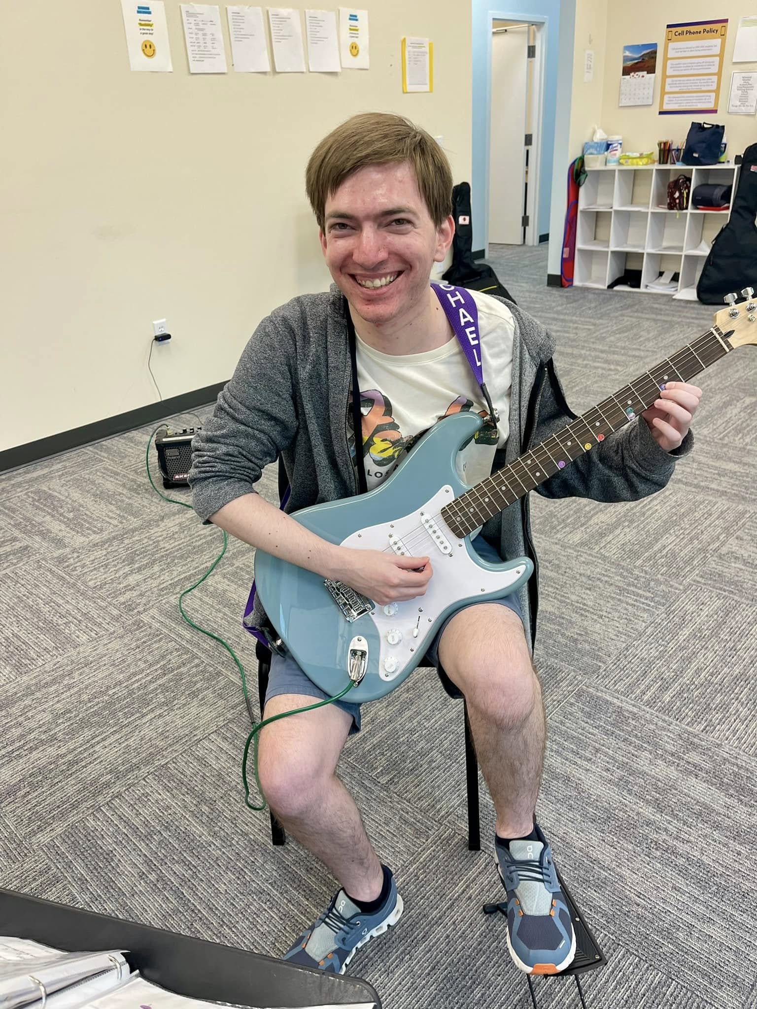 Student with electric guitar, beaming